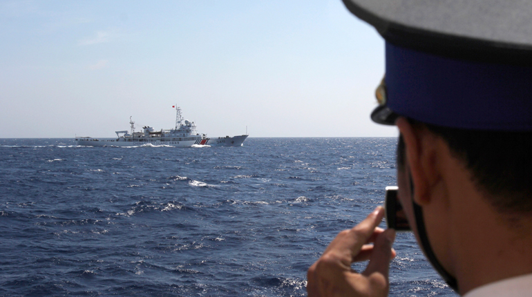 A Vietnamese coastguard officer photographs a Chinese ship in the disputed South China Sea area in May. (PA)