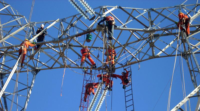 Abengoa employees doing construction work on a transmission tower in Chile.