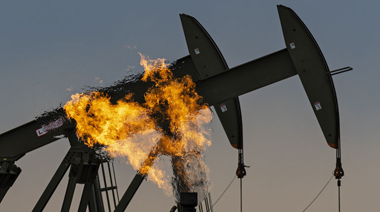 A gas flare beside pumpjacks pumping crude oil at a facility in North Dakota.